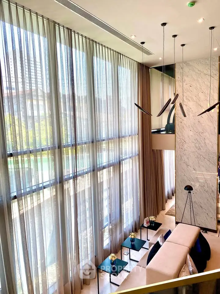 Luxurious high-ceiling living room with floor-to-ceiling windows and modern decor in upscale apartment.