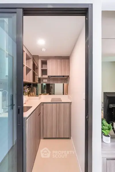 Modern compact kitchen with sleek cabinetry and induction cooktop in a stylish apartment.