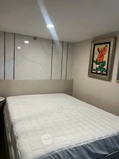 Cozy bedroom with elegant decor and framed artwork, featuring a comfortable bed and stylish wall paneling.