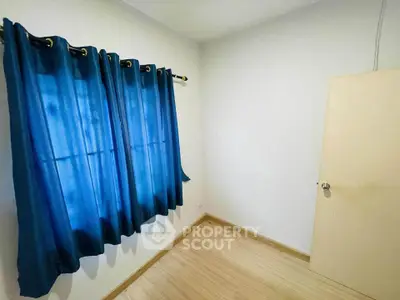 Cozy small room with blue curtains and wooden flooring, perfect for a minimalist setup.