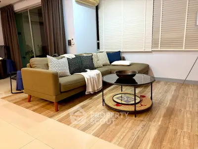 Modern living room with stylish sofa and coffee table, featuring elegant decor and warm lighting.