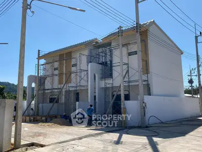 Modern two-story house under construction with scaffolding and workers on site.
