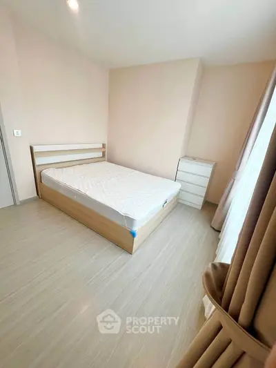 Spacious bedroom with natural light and minimalist design, featuring a comfortable bed and modern dresser.