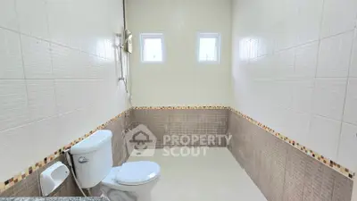 Spacious bathroom with modern fixtures and natural light from small windows.