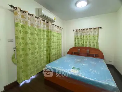 Cozy bedroom with air conditioning and floral curtains, featuring a wooden bed frame and soft lighting.
