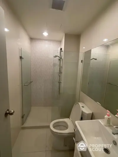 Modern bathroom with glass shower and sleek fixtures in contemporary apartment.