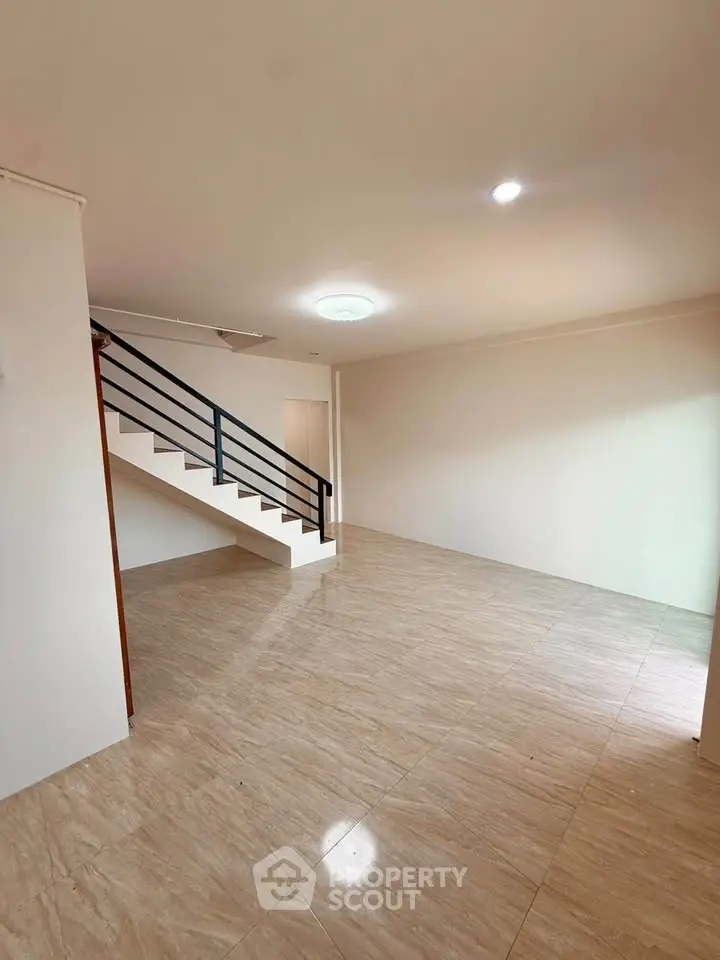 Spacious modern living room with elegant staircase and polished tile flooring.
