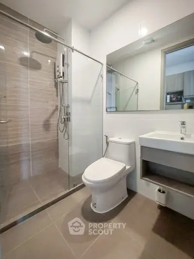 Modern bathroom with glass shower and sleek fixtures in contemporary apartment.