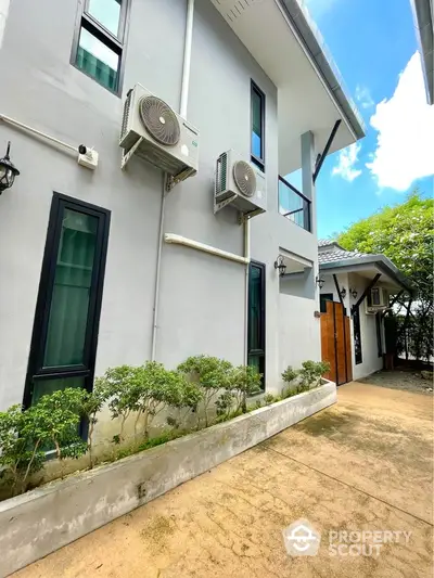 Modern exterior view of a house with air conditioning units and lush greenery