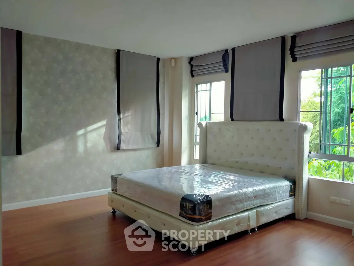 Spacious bedroom with large windows and elegant bed frame in a modern home.