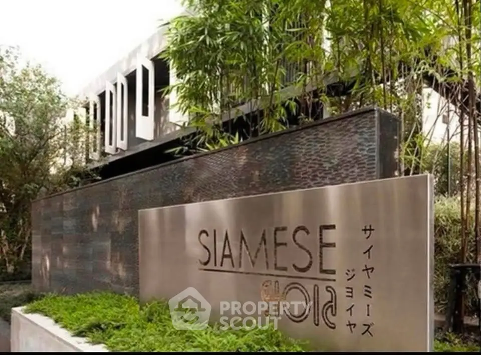 Modern building entrance with lush greenery and stylish signage at Siamese Gioia.