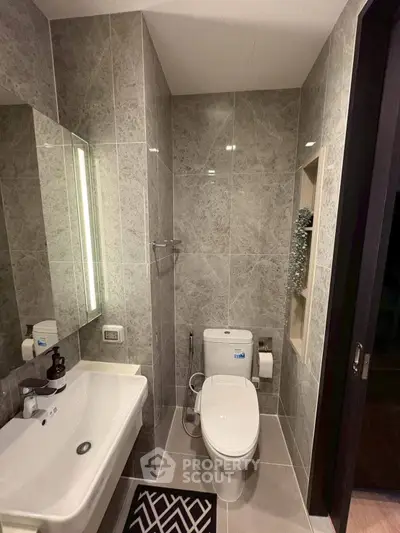 Modern bathroom with sleek fixtures and elegant tile design, featuring a spacious sink and contemporary toilet.