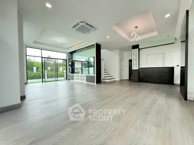 Spacious modern living room with open layout and large windows offering garden view.