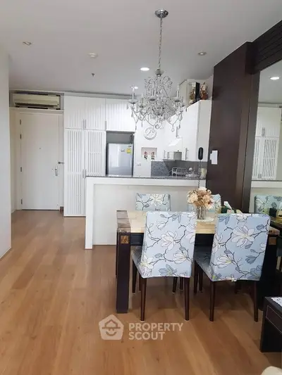 Charming open-layout kitchen and dining area with elegant chandelier and floral chairs.