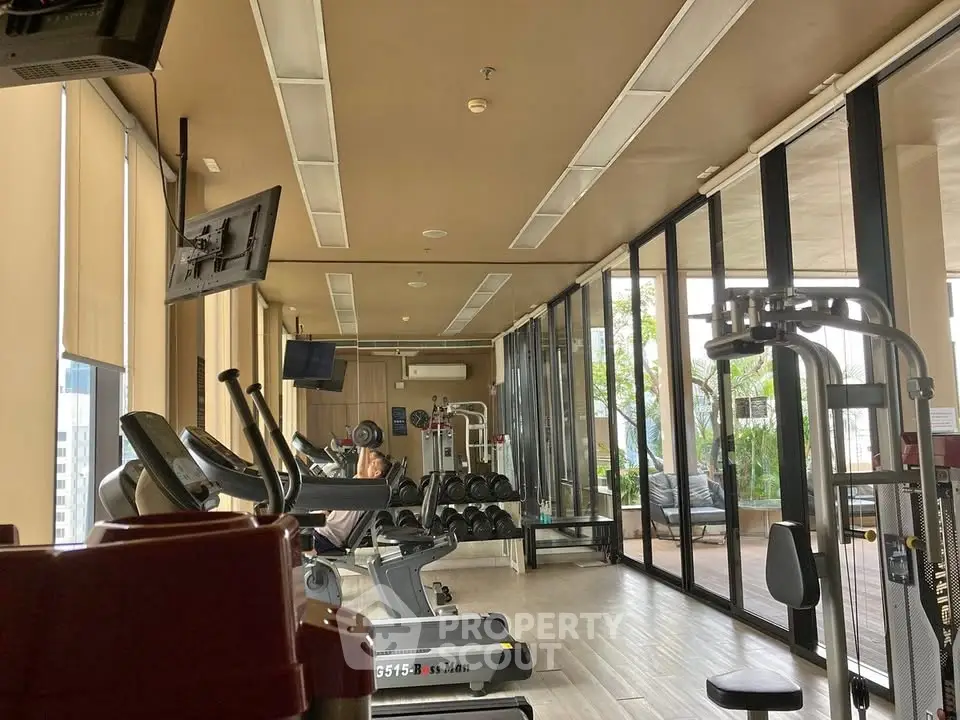 Modern gym with state-of-the-art equipment and floor-to-ceiling windows offering a scenic view.