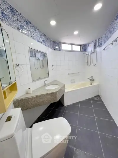 Spacious bathroom with modern fixtures and elegant tile design, featuring a bathtub and ample lighting.