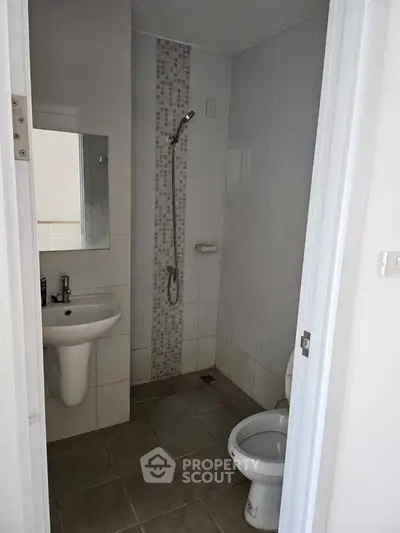 Compact bathroom with shower and modern fixtures in a minimalist design.