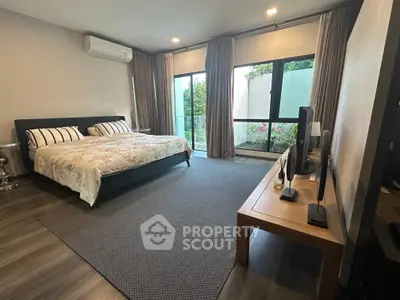 Spacious bedroom with modern decor and large windows offering garden view.
