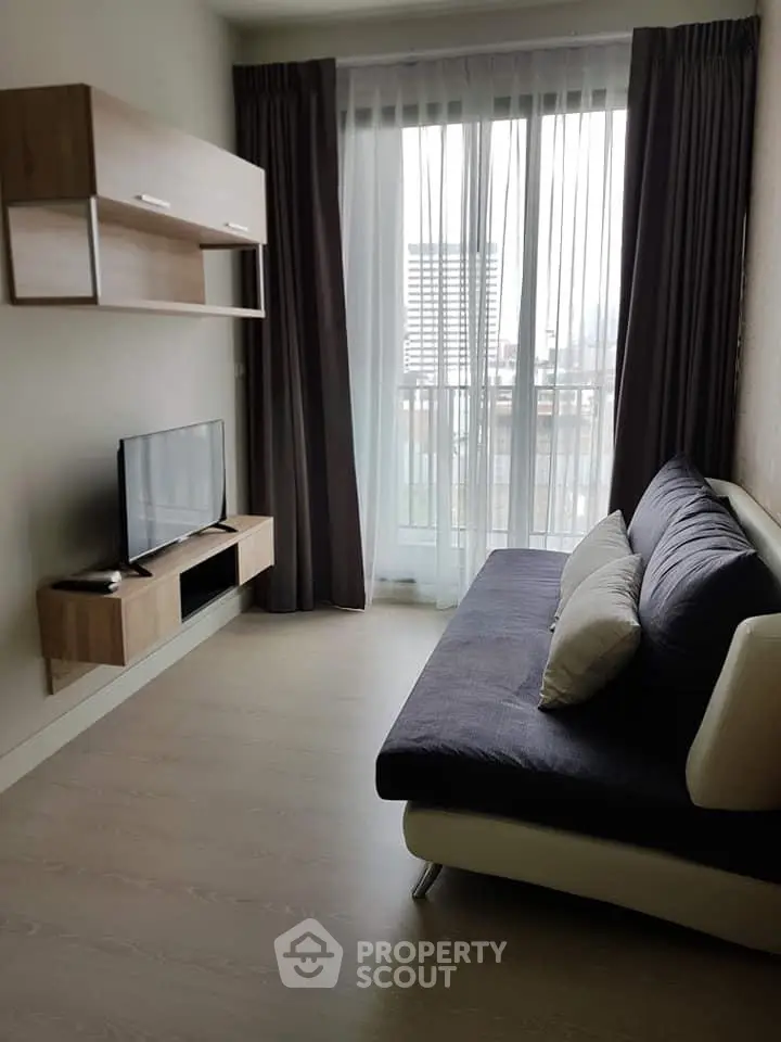 Modern living room with sleek furniture and large window offering city view.