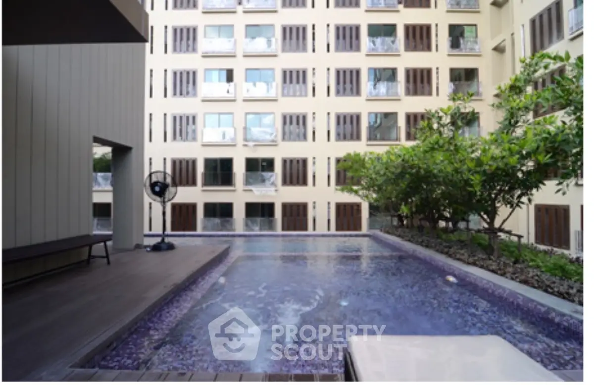 Modern apartment building with a serene outdoor pool and lush greenery, perfect for relaxation and leisure.