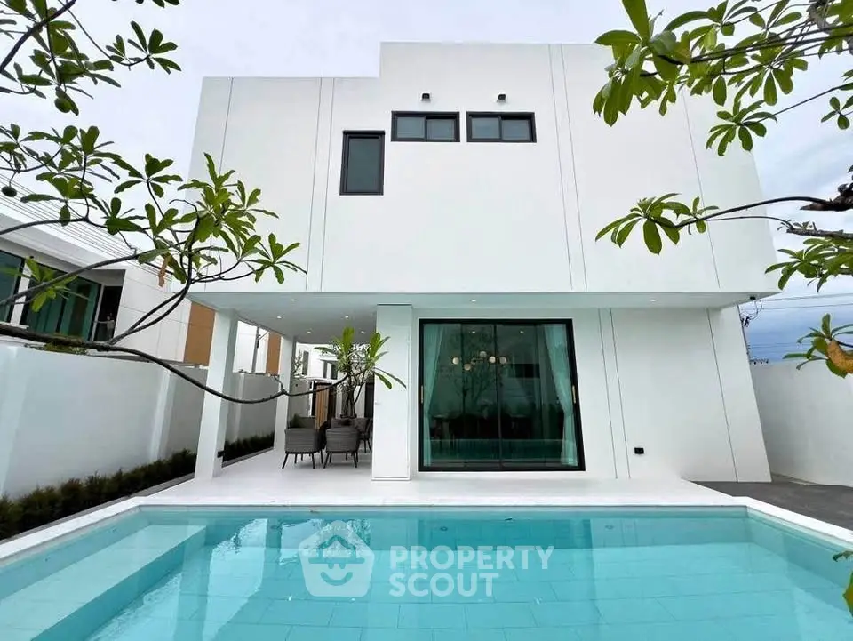 Modern white two-story house with a spacious pool and outdoor seating area.