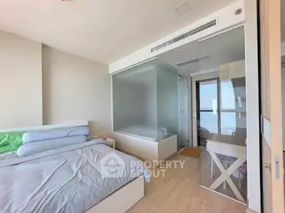 Modern bedroom with glass-enclosed bathroom and ocean view