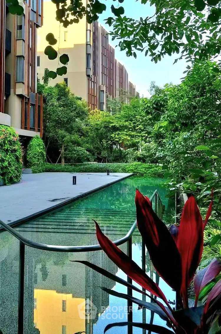 Luxurious residential building with lush garden and serene pool view.
