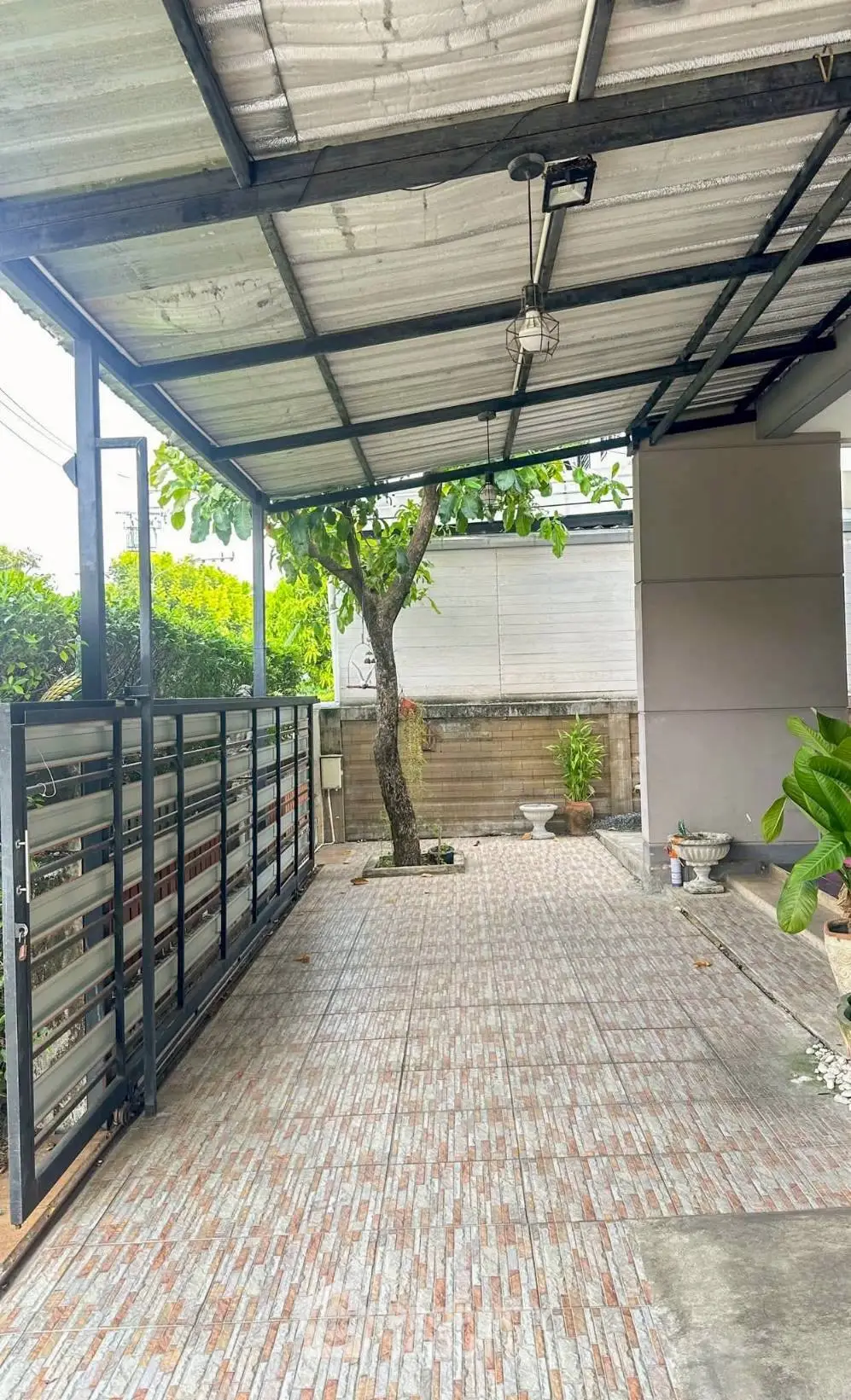 Spacious covered parking area with tiled flooring and garden view, perfect for residential use.