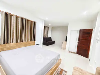 Spacious bedroom with modern decor and cozy seating area, perfect for relaxation.