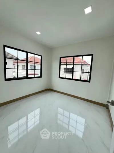 Bright and airy room with large windows and glossy tiled floor, perfect for a modern living space.