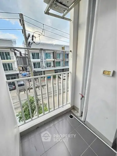Charming small balcony with urban view, perfect for relaxation in a modern townhouse setting.