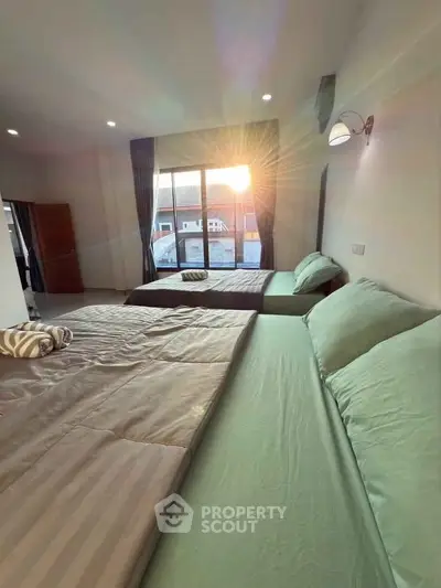 Spacious bedroom with two beds and sunset view through large window.