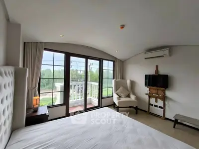 Spacious bedroom with balcony and scenic view, featuring modern furnishings and natural light.