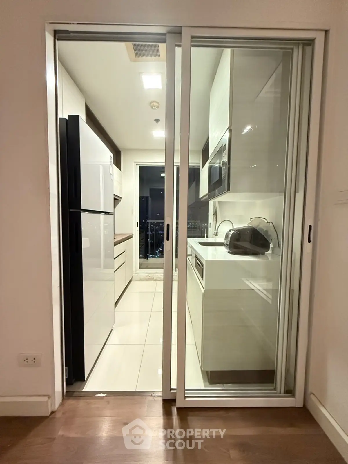 Modern kitchen with sleek appliances and open layout leading to balcony view.