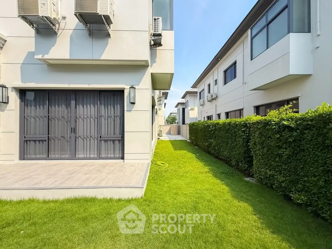Modern townhouse exterior with lush green lawn and sleek design