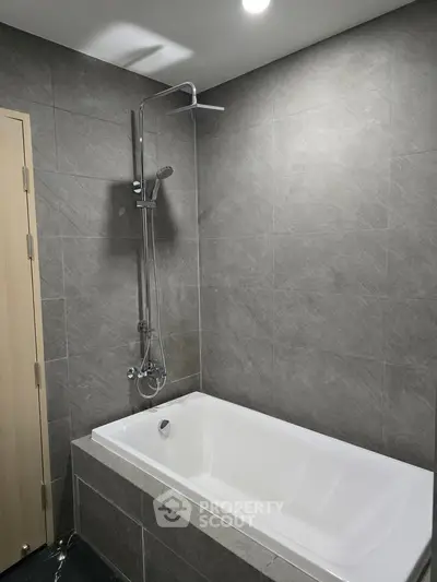 Modern bathroom with sleek gray tiles and a stylish bathtub, perfect for relaxation.