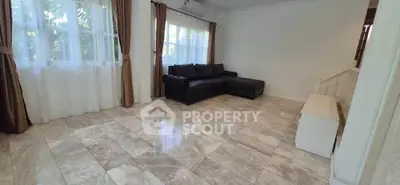 Spacious living room with elegant tile flooring and large windows for natural light.