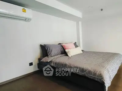 Modern bedroom with stylish bedding and air conditioning in a contemporary apartment.