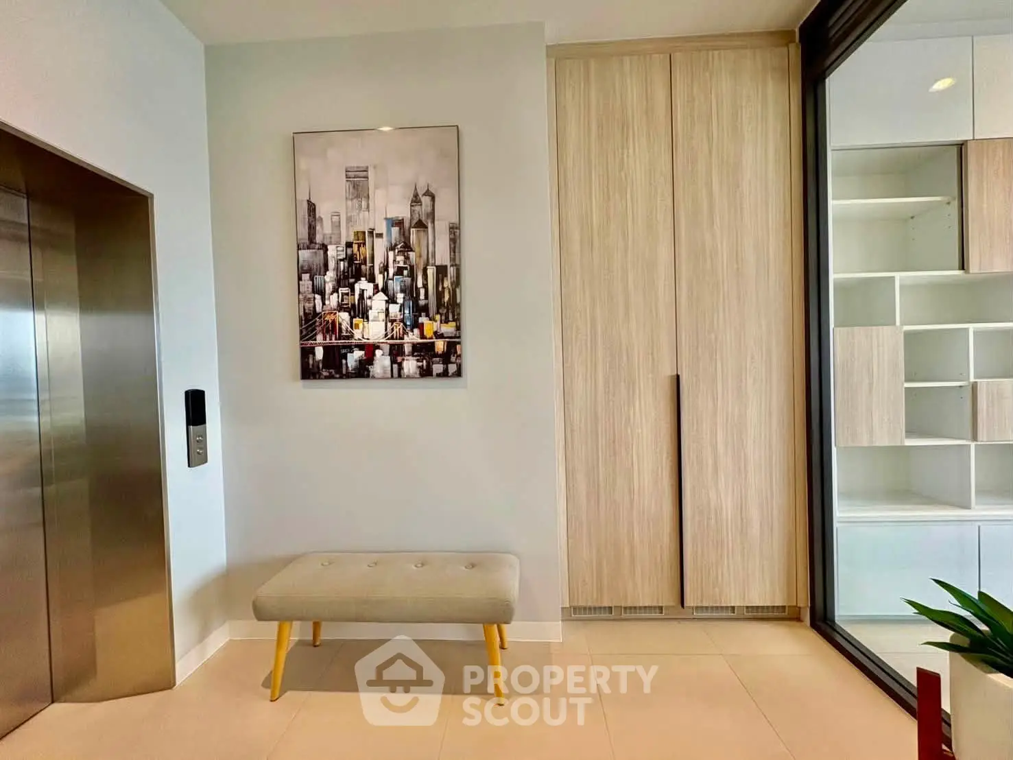 Modern apartment entrance with elevator and stylish decor, featuring a cityscape painting and sleek storage solutions.
