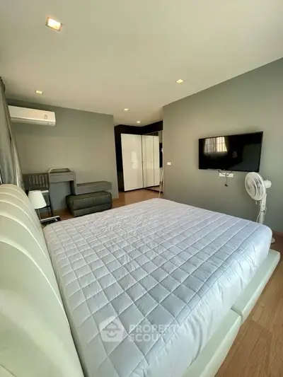 Spacious modern bedroom with sleek design and wall-mounted TV, perfect for comfort and relaxation.