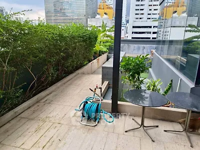 Spacious urban balcony with lush greenery and city views, perfect for relaxation and outdoor dining.