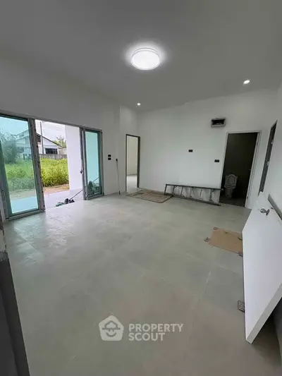 Spacious unfurnished room with large windows and tiled floor, ideal for customization.