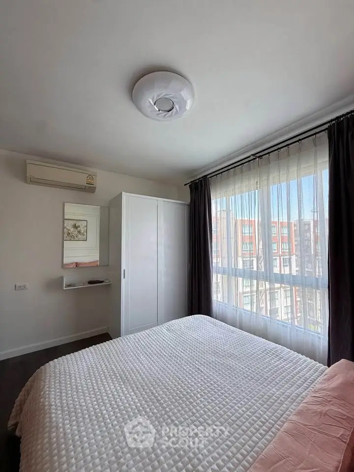 Bright bedroom with large window and modern decor in urban apartment