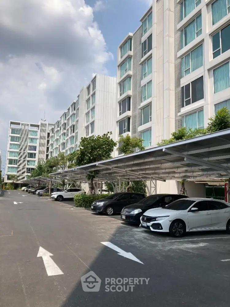 Modern apartment building with spacious parking area and lush greenery