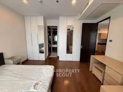 Spacious bedroom with modern furnishings and wooden flooring in a stylish apartment.