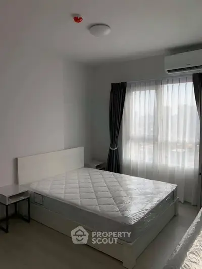 Spacious bedroom with large window and natural light in modern apartment.