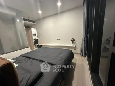 Modern bedroom with sleek design and large window offering city views.