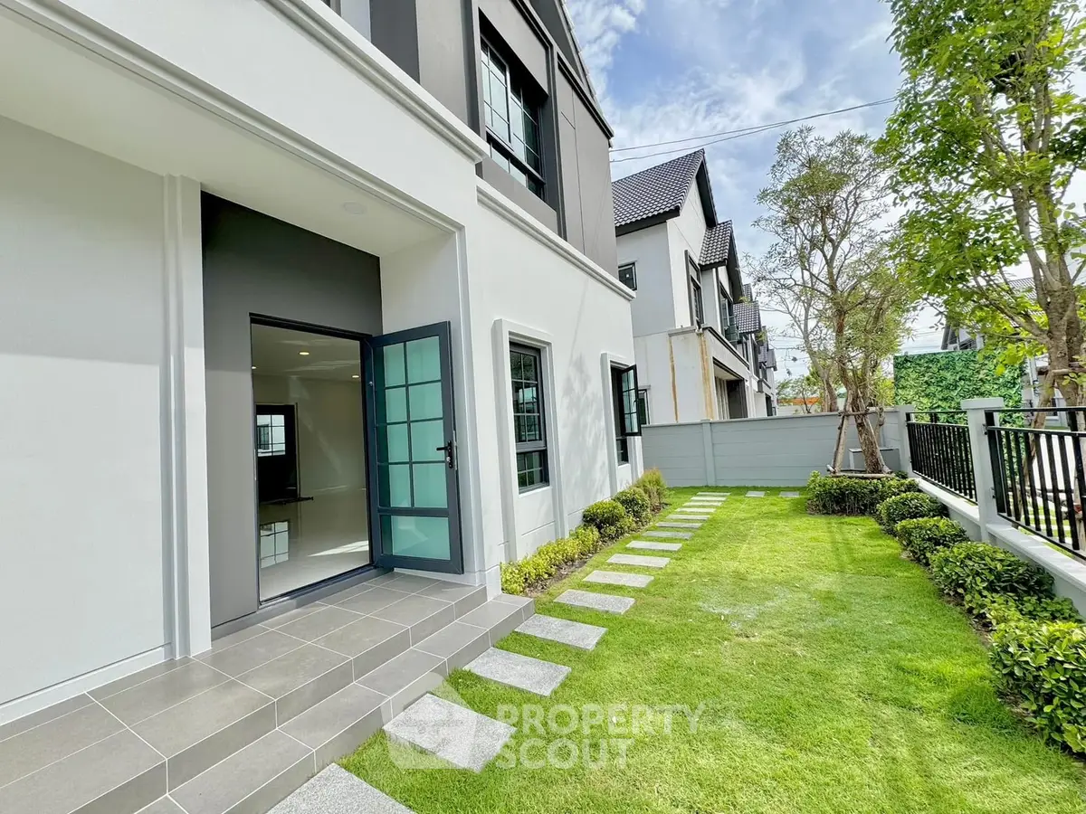 Charming modern townhouse with lush green garden and stylish exterior design.