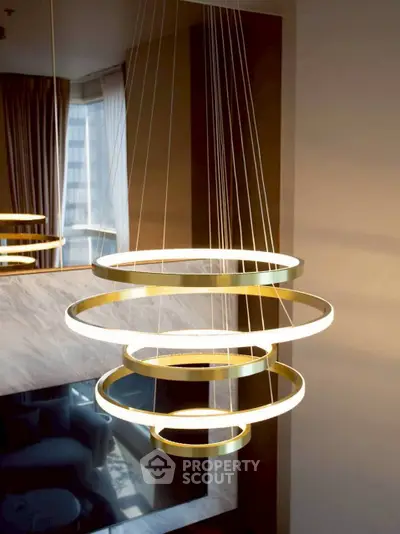 Elegant modern chandelier in luxurious living room with large windows and city view.
