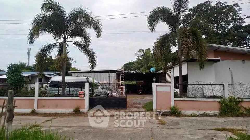 Spacious property with palm trees and gated entrance, ideal for residential or commercial use.